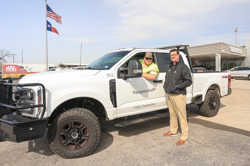 Paul Smith stands next to a City of Nacogdoches work truck and employee.